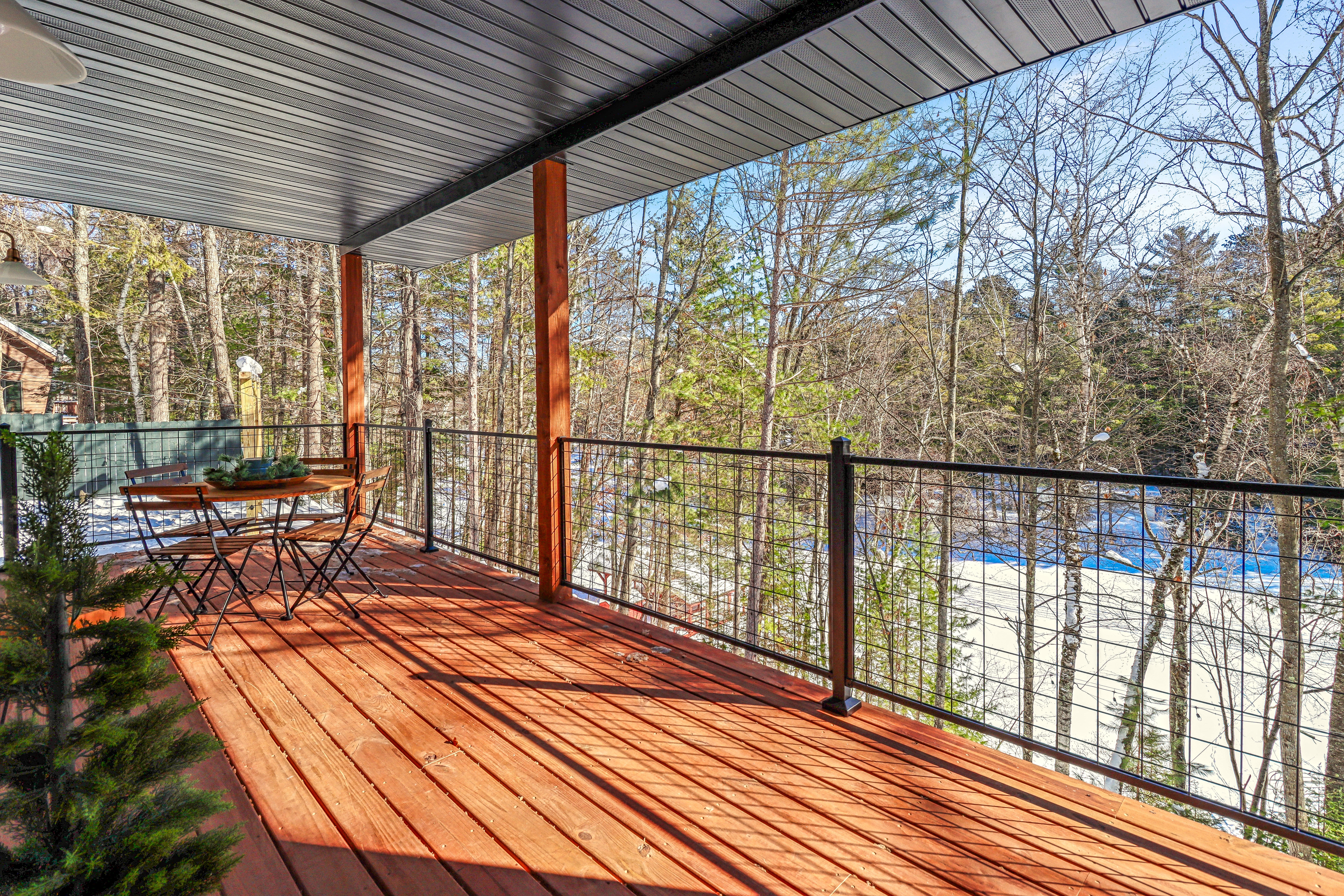 Expansive covered porch surrounded by Northwoods trees